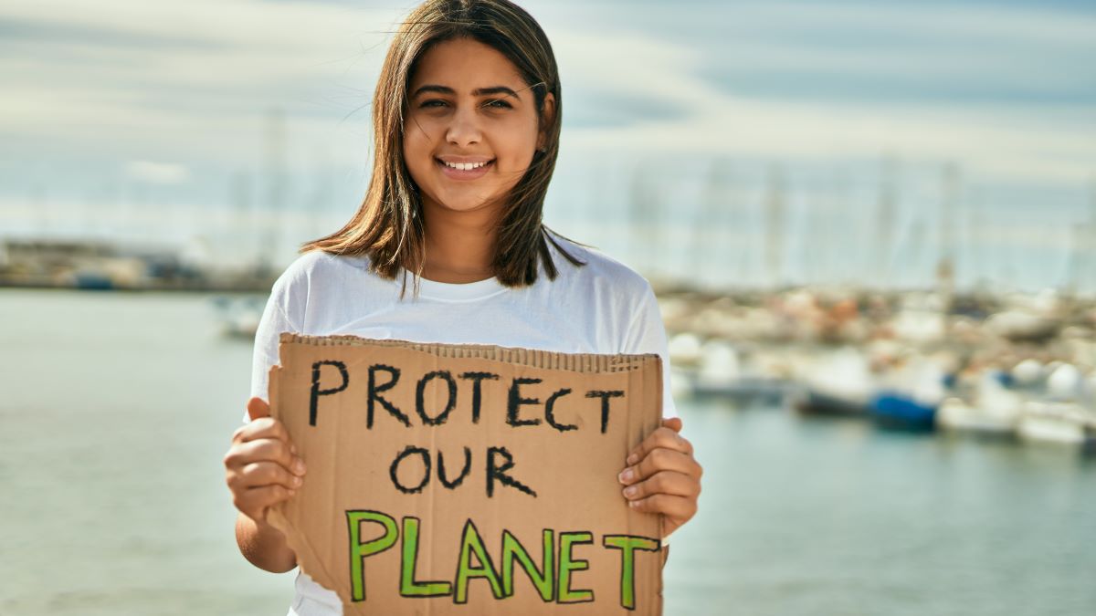 Latina girl holding "protect our planet" sign