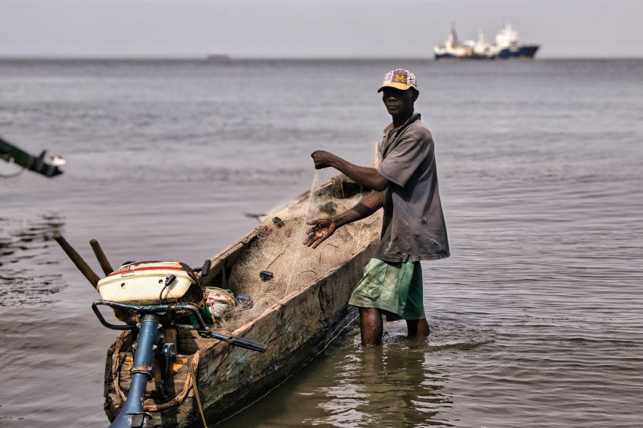 Man sorts fishing net in boat, Freetown, Sierra Leone