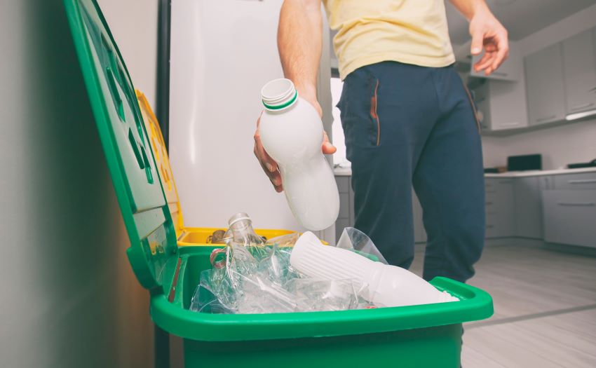 Man putting plastic bottle into recycling bin
