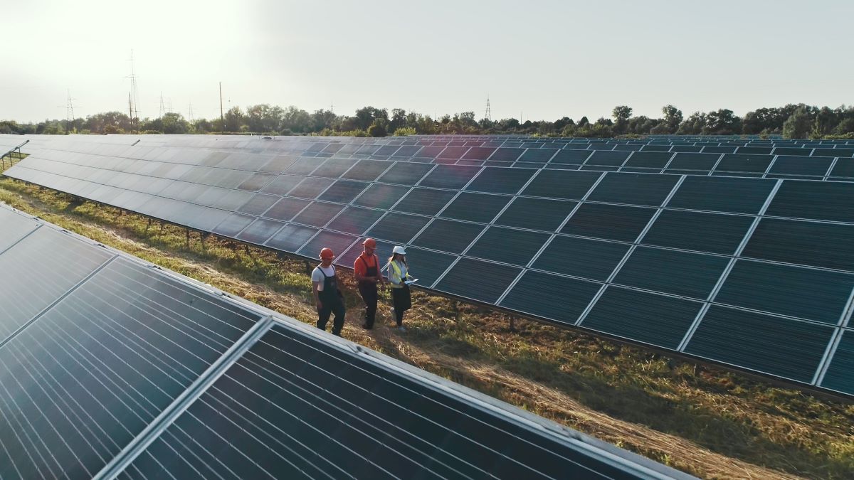 Technicians walking between solar arrays on a solar farm