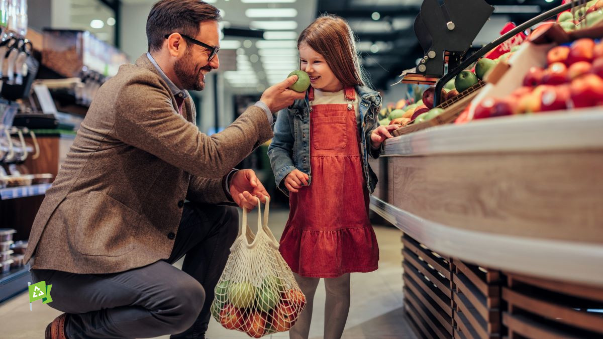 Father and daughter put apples in reusable bag at grocery store